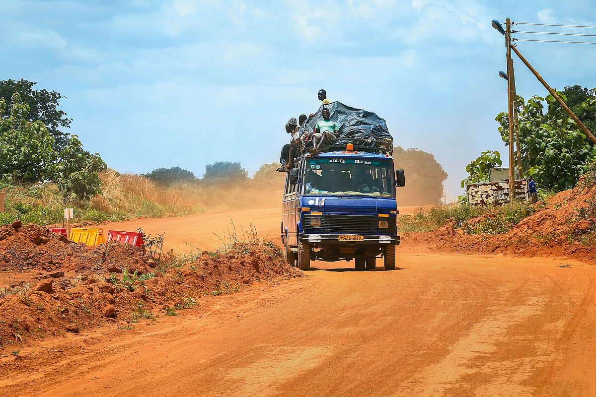 Accra, Ghana - April 01, 2022: Colorful African Public Mini Bus on the Dusty Road in the heart of Ghana